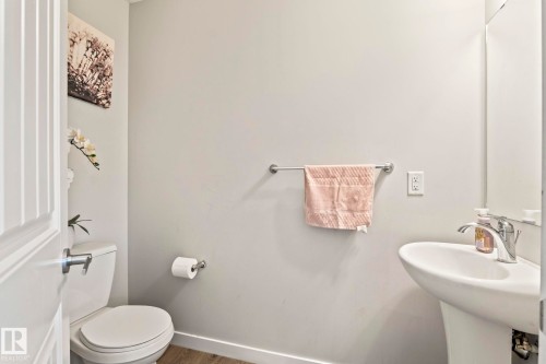 This powder room features a white pedestal sink with a chrome faucet, a white toilet, and a towel bar - 483 Ebbers Way Nw, Edmonton, AB - Indoor Photo Showing Bathroom