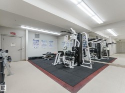 Well-equipped fitness room featuring a multi-station gym, weight bench, exercise mat flooring, and mirrored wall - 