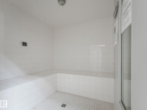 The property features a tiled room with built-in bench seating and a tiled floor with a drain - 412 12408 15 Avenue, Edmonton, AB - Indoor Photo Showing Bathroom