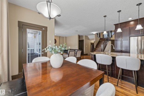 The spacious interior features hardwood floors, a kitchen island with seating, dark wood cabinetry, and stainless steel appliances - 1014 Hope Road, Edmonton, AB - Indoor Photo Showing Dining Room