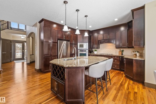 The kitchen features hardwood floors, dark wood cabinetry, granite countertops, and stainless steel appliances - 1014 Hope Road, Edmonton, AB - Indoor Photo Showing Kitchen With Upgraded Kitchen