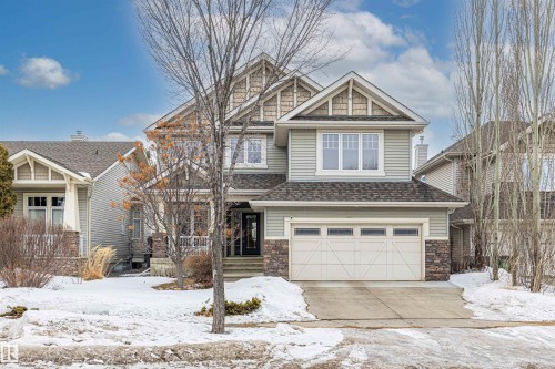 The property presents a two-story exterior with light green siding and stone accents, featuring a prominent front-facing gable with decorative shingle siding - 1014 Hope Road, Edmonton, AB - Outdoor With Facade