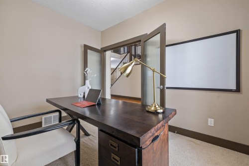 This space features carpeted flooring, light-colored walls, and a pair of glass-paneled doors - 1014 Hope Road, Edmonton, AB - Indoor