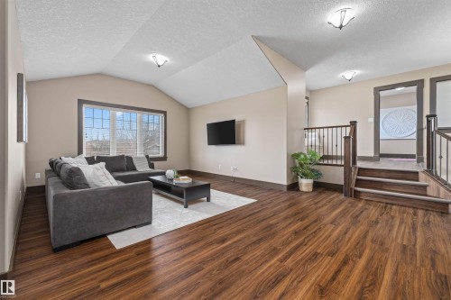 Family Room featuring vaulted ceilings, a large window with horizontal blinds, and rich wood-toned flooring - 1014 Hope Road, Edmonton, AB - Indoor