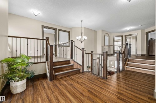 A grand entryway featuring rich hardwood flooring, dark wood staircases with wrought iron railings, and overhead lighting - 1014 Hope Road, Edmonton, AB - Indoor Photo Showing Other Room