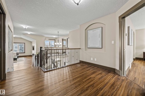 The property features rich wood flooring throughout, a decorative wall niche, and an open railing overlooking the space below - 1014 Hope Road, Edmonton, AB - Indoor Photo Showing Other Room