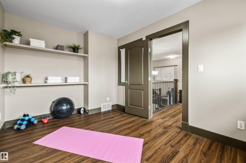 Upper floor bedroom features warm-toned flooring and built-in shelving, offering practical storage solutions - 1014 Hope Road, Edmonton, AB - Indoor