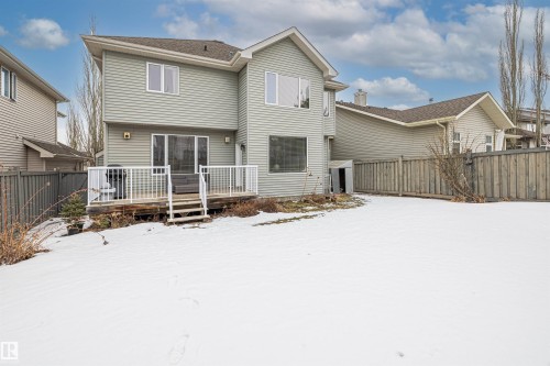 Rear exterior of the property featuring light grey siding, a white-railed deck with steps, and a fenced yard - 1014 Hope Road, Edmonton, AB - Outdoor
