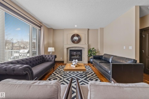 Bright living area with hardwood floors, a stone fireplace, and large sliding glass doors - 1014 Hope Road, Edmonton, AB - Indoor Photo Showing Living Room With Fireplace