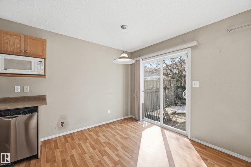 The eat-in kitchen features wood-look flooring, light wood cabinetry, and a sliding glass door providing natural light and access to the outdoors - 53 287 Macewan Road, Edmonton, AB - Indoor With Fireplace