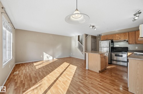 The main living area features hardwood flooring, a bright window, and neutral wall tones - 53 287 Macewan Road, Edmonton, AB - Indoor Photo Showing Kitchen