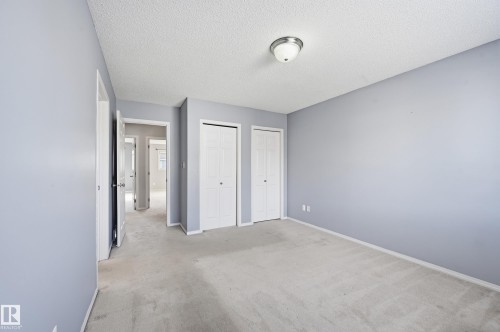 Room with light blue walls, light-colored carpet, a ceiling-mounted light fixture, and two white bi-fold closet doors - 53 287 Macewan Road, Edmonton, AB - Indoor Photo Showing Other Room
