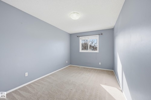 This room features light blue walls, a window providing natural light, and neutral-toned carpeting - 53 287 Macewan Road, Edmonton, AB - Indoor Photo Showing Other Room