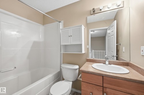 Bathroom featuring a white bathtub, a toilet, and a vanity with a white sink and wooden cabinetry - 53 287 Macewan Road, Edmonton, AB - Indoor Photo Showing Bathroom