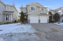 This property features a light-colored exterior with a front entry, and a two-car garage with white doors - 53 287 Macewan Road, Edmonton, AB  - Outdoor With Facade 