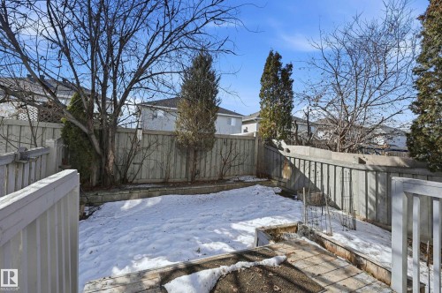 The property features a fenced backyard with mature trees and a raised garden bed - 53 287 Macewan Road, Edmonton, AB - Outdoor