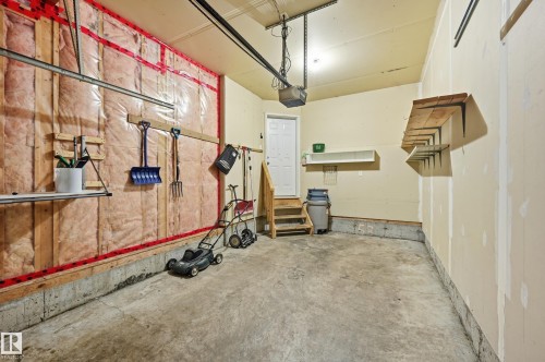 The garage features a concrete floor, exposed insulation on one wall, and a white access door - 53 287 Macewan Road, Edmonton, AB - Indoor Photo Showing Gym Room