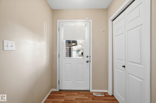 Entryway featuring wood-look flooring, a white door with a window, and a white bi-fold closet door - 53 287 Macewan Road, Edmonton, AB - Indoor Photo Showing Other Room