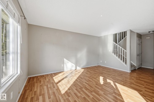 The living area features wood plank flooring and a window with blinds - 53 287 Macewan Road, Edmonton, AB - Indoor Photo Showing Other Room