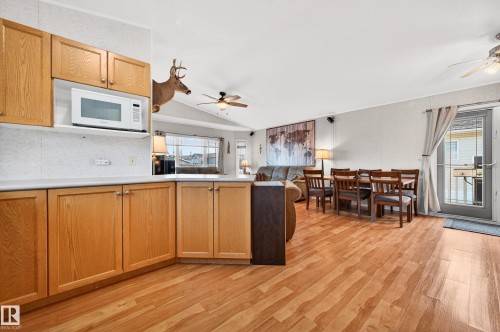Open concept living area featuring wood laminate flooring, a ceiling fan, and a kitchen with light wood cabinetry and a white microwave - 1727 Jubilee Loop, Sherwood Park, AB - Indoor Photo Showing Kitchen