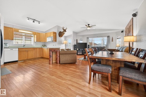 Open concept living area with hardwood floors, a kitchen featuring wood cabinetry and white appliances, and a dining area with a wooden table - 1727 Jubilee Loop, Sherwood Park, AB - Indoor