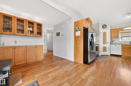 The kitchen features light wood cabinetry, with some upper cabinets including glass inserts, and a built-in stainless steel refrigerator - 1727 Jubilee Loop, Sherwood Park, AB - Indoor Photo Showing Kitchen