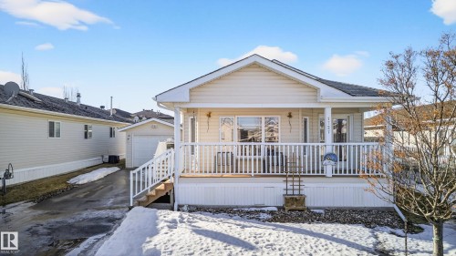 The property features a front porch with white railings and an exterior of light-colored siding - 1727 Jubilee Loop, Sherwood Park, AB - Outdoor With Deck Patio Veranda