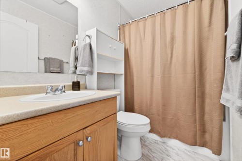 Bathroom featuring a vanity with a light-colored countertop and wood cabinetry, a white toilet, and a shower with a shower curtain - 1727 Jubilee Loop, Sherwood Park, AB - Indoor Photo Showing Bathroom