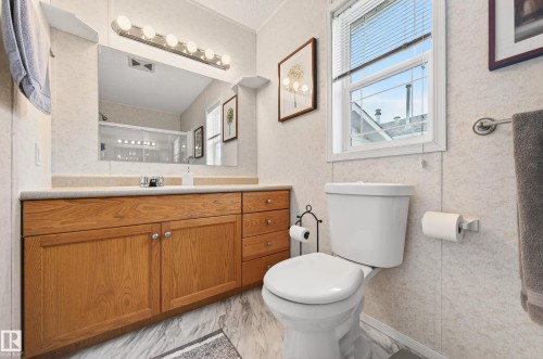 The bathroom features a light wood vanity with a light-colored countertop and a mirror with a light fixture - 1727 Jubilee Loop, Sherwood Park, AB - Indoor Photo Showing Bathroom