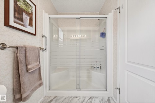 The bathroom features a shower with sliding glass doors, a built-in shower bench, and a grab bar - 1727 Jubilee Loop, Sherwood Park, AB - Indoor Photo Showing Bathroom