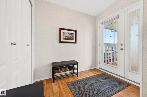 The entryway features warm-toned hardwood flooring and a white paneled door with glass inserts, allowing natural light into the space - 1727 Jubilee Loop, Sherwood Park, AB - Indoor Photo Showing Other Room