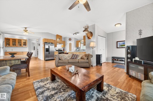 Open concept living space featuring wood flooring, a ceiling fan, and a kitchen with wooden cabinetry and stainless steel appliances - 1727 Jubilee Loop, Sherwood Park, AB - Indoor Photo Showing Living Room