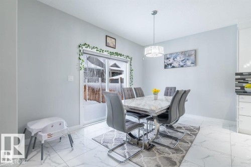 Dining area featuring light-colored walls, white tiled flooring, and a sliding glass door providing external views - 3608 46 Avenue, Beaumont, AB - Indoor Photo Showing Dining Room