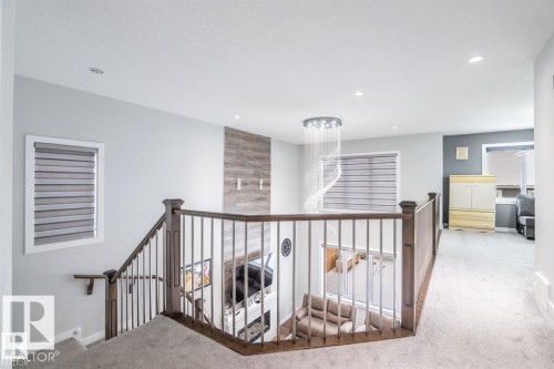The property features a staircase with a wooden handrail and metal spindles, leading to a carpeted landing - 3608 46 Avenue, Beaumont, AB - Indoor Photo Showing Other Room