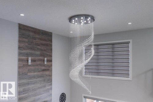 Interior space featuring a modern spiral chandelier, recessed lighting, a window with horizontal blinds, and an accent wall with a wood plank design - 3608 46 Avenue, Beaumont, AB - Indoor Photo Showing Other Room