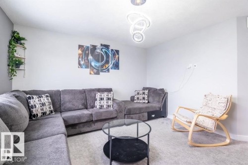 Living area featuring light gray walls, a light gray carpet, and a modern ceiling light fixture - 3608 46 Avenue, Beaumont, AB - Indoor Photo Showing Living Room