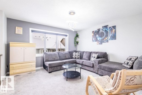 Bright living area featuring a large window, a modern light fixture, and light-toned carpeting - 3608 46 Avenue, Beaumont, AB - Indoor Photo Showing Living Room