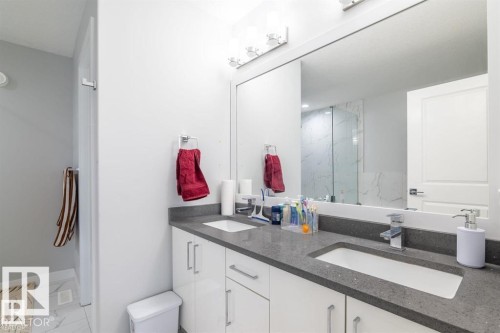 Well-appointed bathroom featuring a double vanity with white cabinetry, a grey countertop, and a large mirror - 3608 46 Avenue, Beaumont, AB - Indoor Photo Showing Bathroom