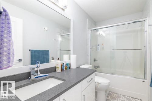 This bathroom features a vanity with a dark speckled countertop and an integrated rectangular sink - 3608 46 Avenue, Beaumont, AB - Indoor Photo Showing Bathroom