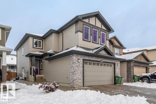 The property features a two-story exterior with light-colored siding, a stone facade, and dark trim details - 3608 46 Avenue, Beaumont, AB - Outdoor With Facade
