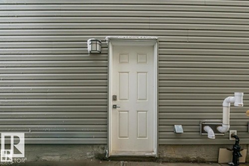 The property features light grey horizontal siding and a white exterior door with a paneled design - 3608 46 Avenue, Beaumont, AB - Outdoor With Exterior