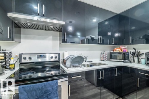 The kitchen features dark cabinetry, a stainless steel range, and a stainless steel range hood - 3608 46 Avenue, Beaumont, AB - Indoor Photo Showing Kitchen