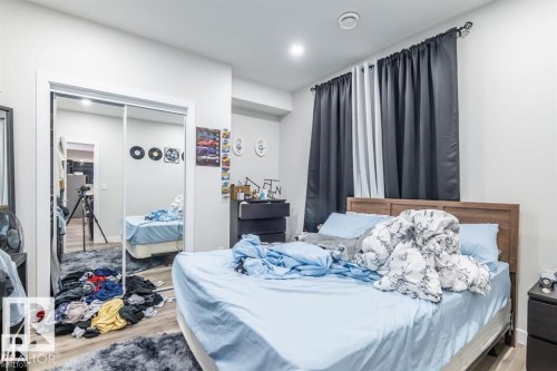 The room features a wooden bed frame, a mirrored closet, and dark curtains - 3608 46 Avenue, Beaumont, AB - Indoor Photo Showing Bedroom