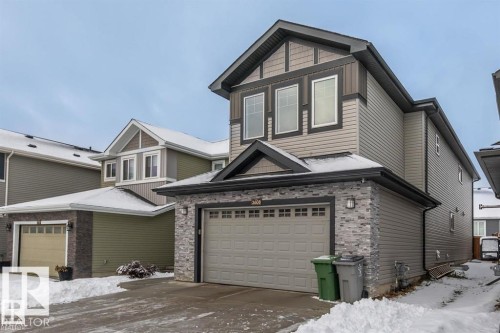 The property features a two-story design with a prominent gable roof, light gray siding, and stone accents on the facade - 3608 46 Avenue, Beaumont, AB - Outdoor
