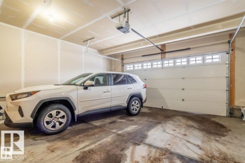 The property features an attached garage with a concrete floor and an overhead door with frosted window inserts - 3608 46 Avenue, Beaumont, AB - Indoor Photo Showing Garage