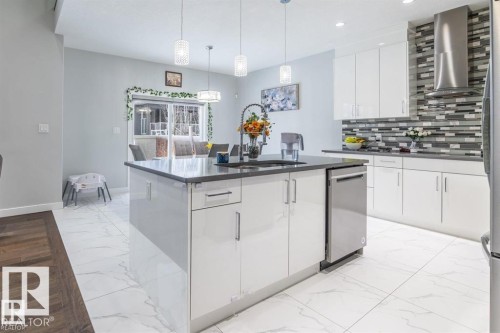 The kitchen features an island with a dark countertop and a stainless steel dishwasher - 3608 46 Avenue, Beaumont, AB - Indoor Photo Showing Kitchen With Upgraded Kitchen