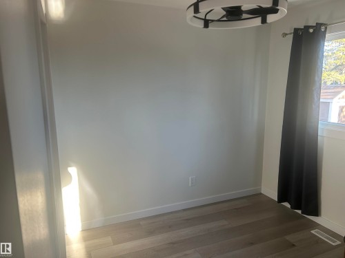 This room features light-colored walls, wood-look flooring, and a modern ceiling light fixture - 14911 77 Street Nw, Edmonton, AB - Indoor Photo Showing Other Room