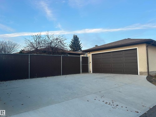 The property features a concrete driveway leading to a two-car garage with a brown door - 14911 77 Street Nw, Edmonton, AB - Outdoor