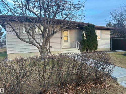 The property features light-colored horizontal siding, a dark roof, and a mature tree in the front yard - 14911 77 Street Nw, Edmonton, AB - Outdoor
