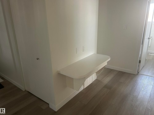 Bedroom featuring a built-in desk or vanity, white walls, light-toned flooring, and a white closet with bifold doors - 14911 77 Street Nw, Edmonton, AB - Indoor Photo Showing Other Room